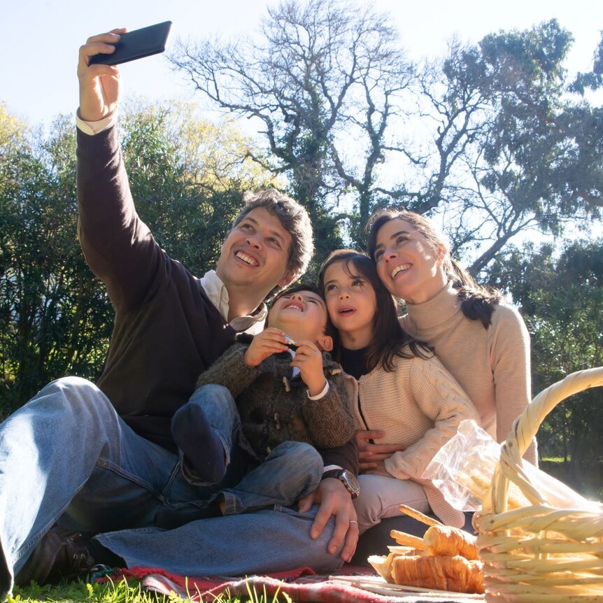 Father takes family selfie at a picnic