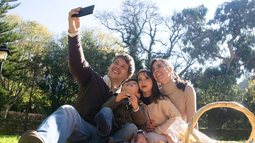 Father takes family selfie at a picnic