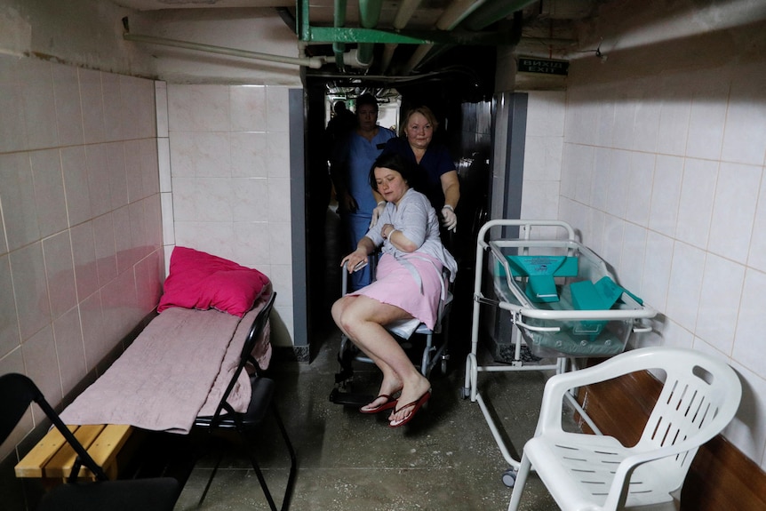 Nurses help a patient to take shelter in the basement of a perinatal centre 