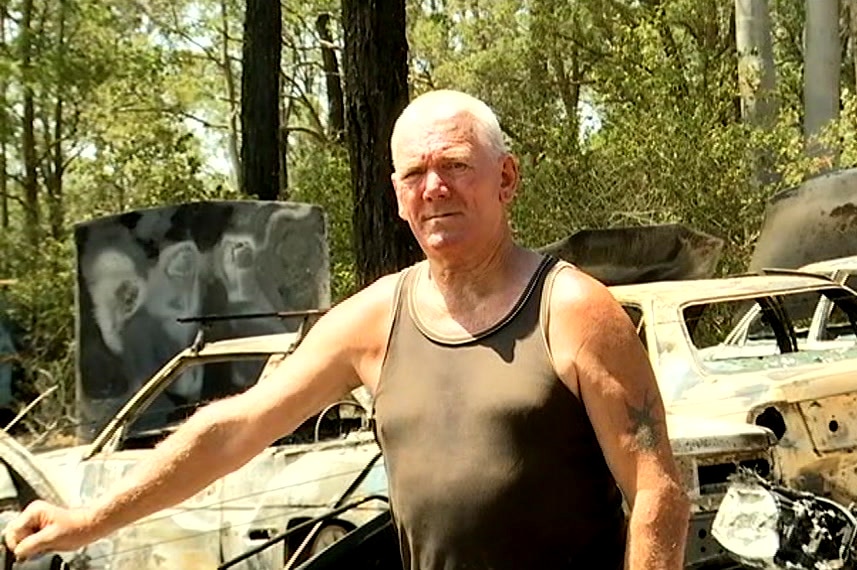 Derek Eastham stands in a singlet, leaning against a car.