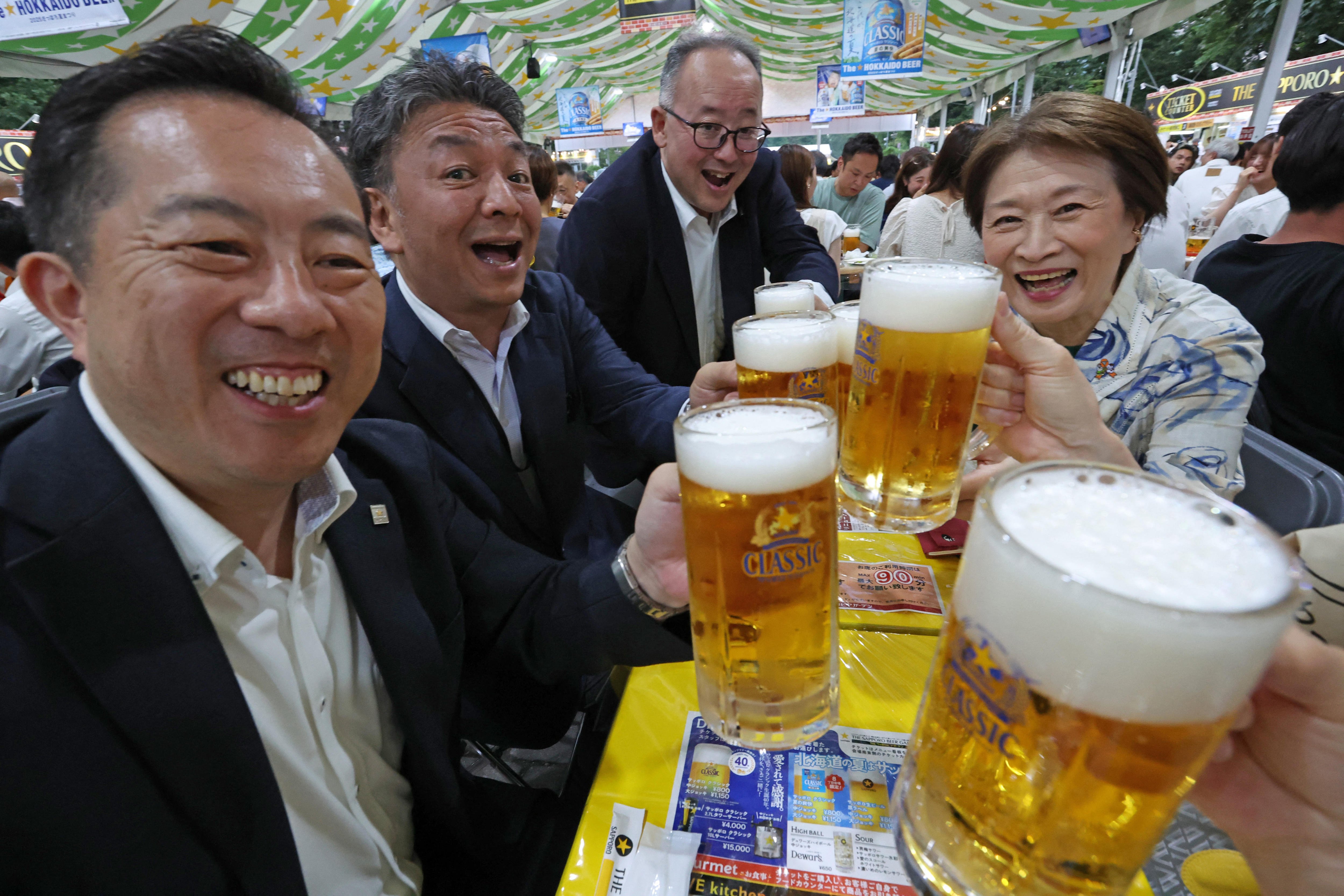 La gente brinda con vasos de cerveza en una taberna al aire libre en Sapporo, Japón