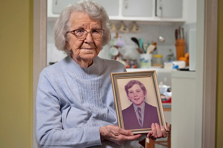Image of an elderly woman holding a photograph of a young boy.
