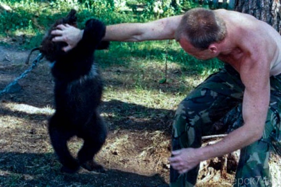 A man playing with a young bear cub.