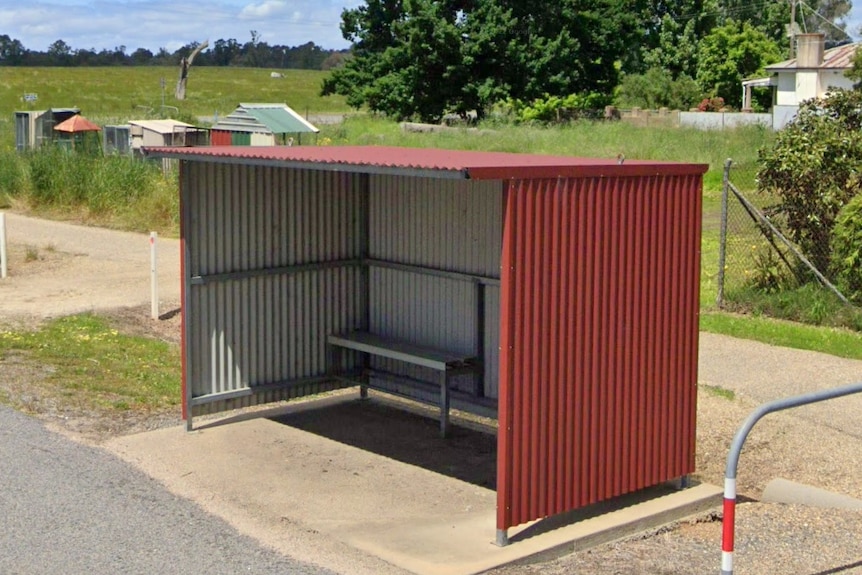 A small bus shelter on the side of a country road.