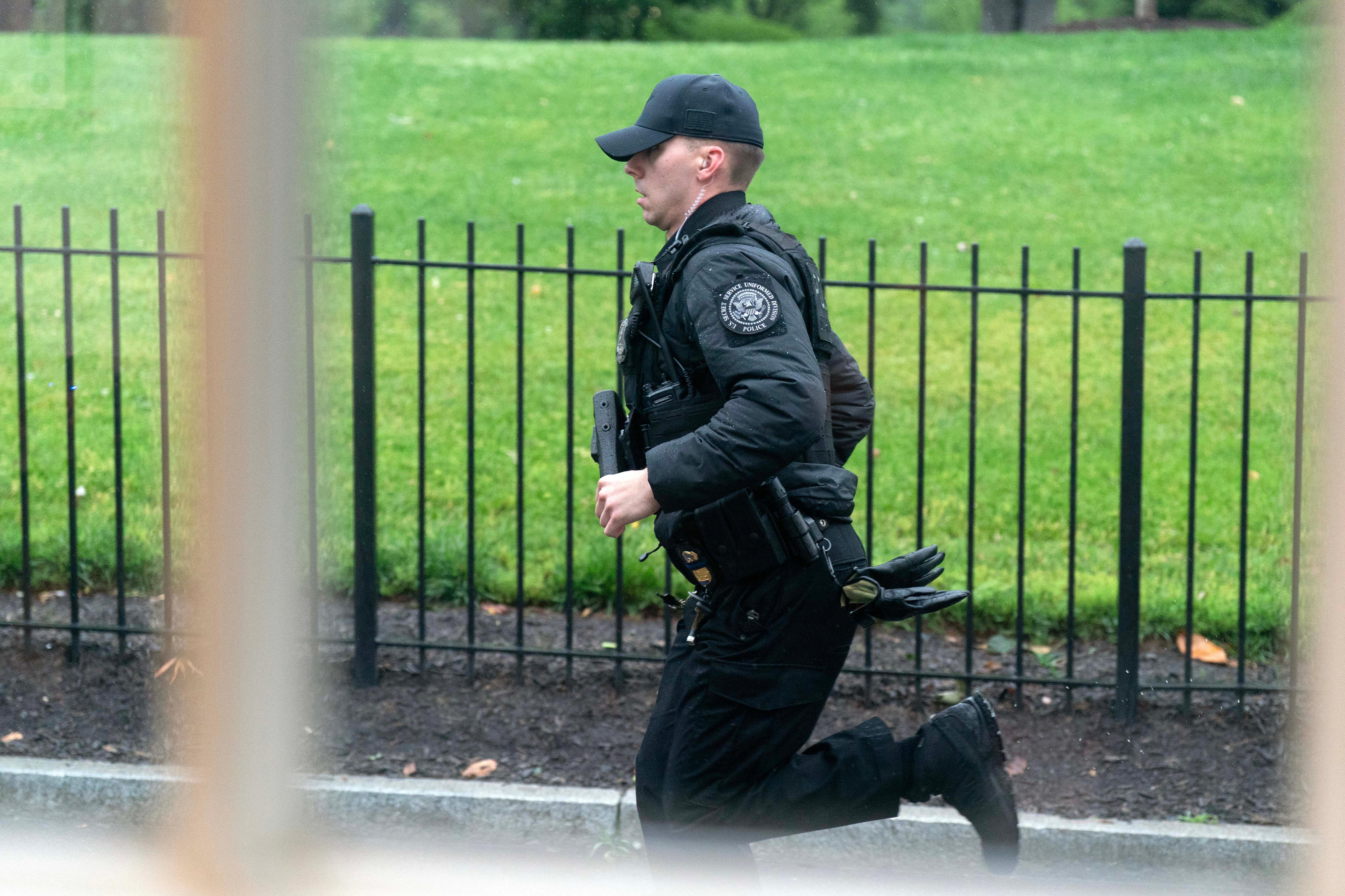 A Secret Service officer sprints through the White House grounds after gunshots were heard. 