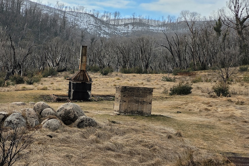 Two stone hearths remain standing on a burnt mountainous landscape