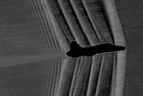Grainy silhouette image of a jet with visible soundwaves peeling back from the front of the jet.