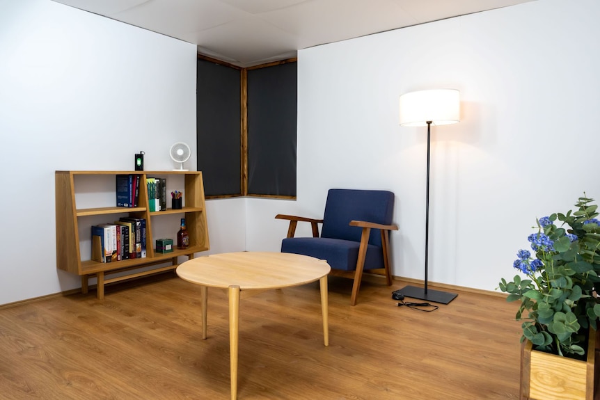 A furnished room with chair, table, bookshelf and lamp