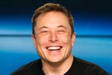 Tesla CEO Elon Musk smiles at a press conference.