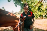 Doomadgee State School student Thomasina Foot smiling at the camera, holding a horses bridle.