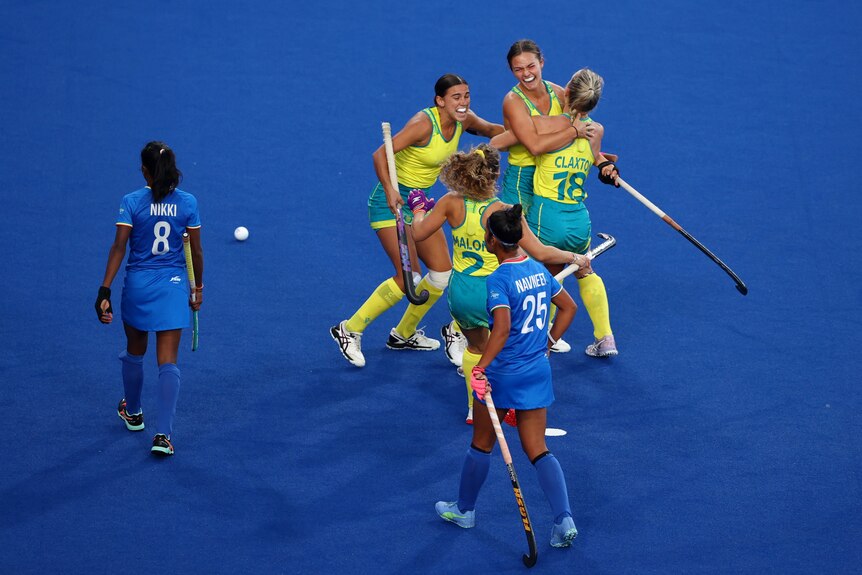 Australian hockey players hug after a goal in the Commonwealth Games semi-final against India.