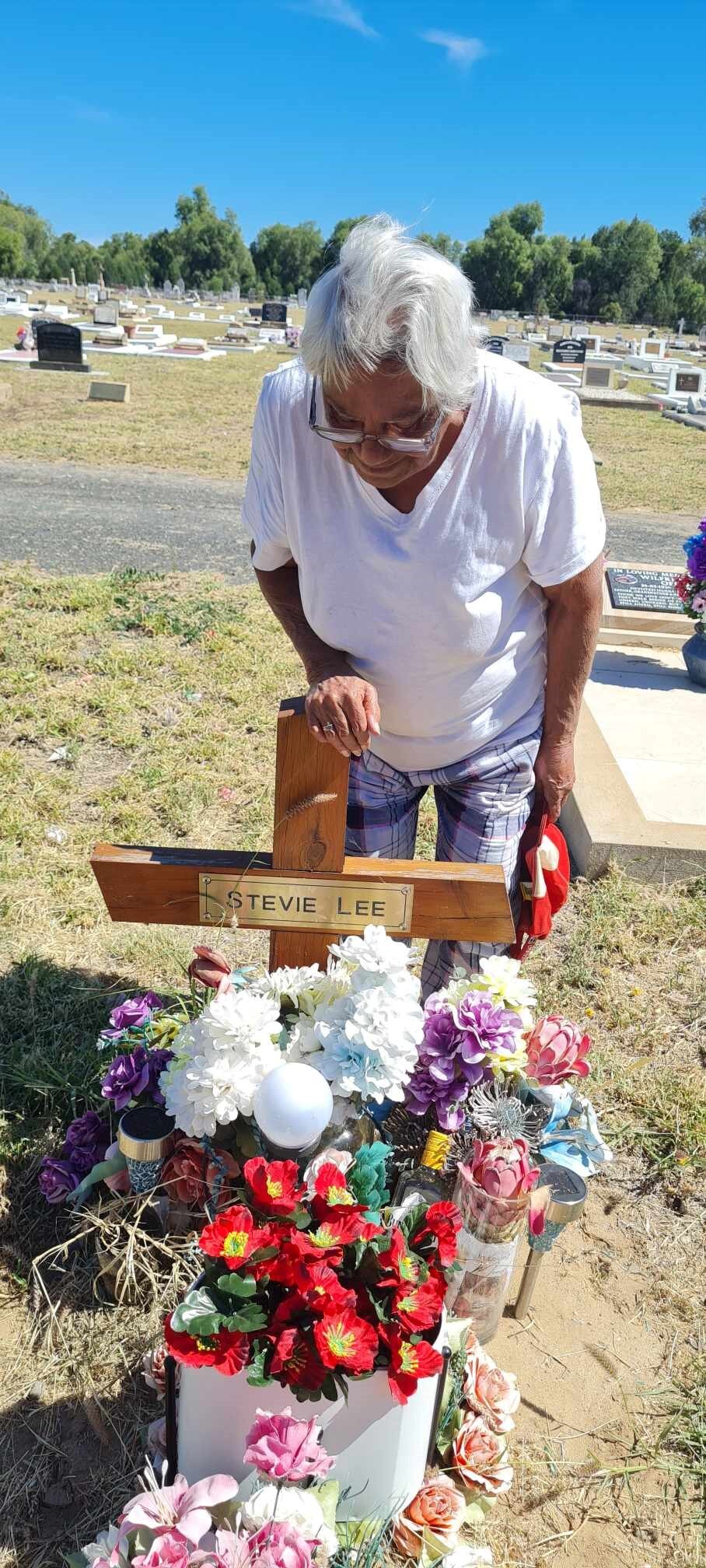 A woman standing next to a grave with a cross on it