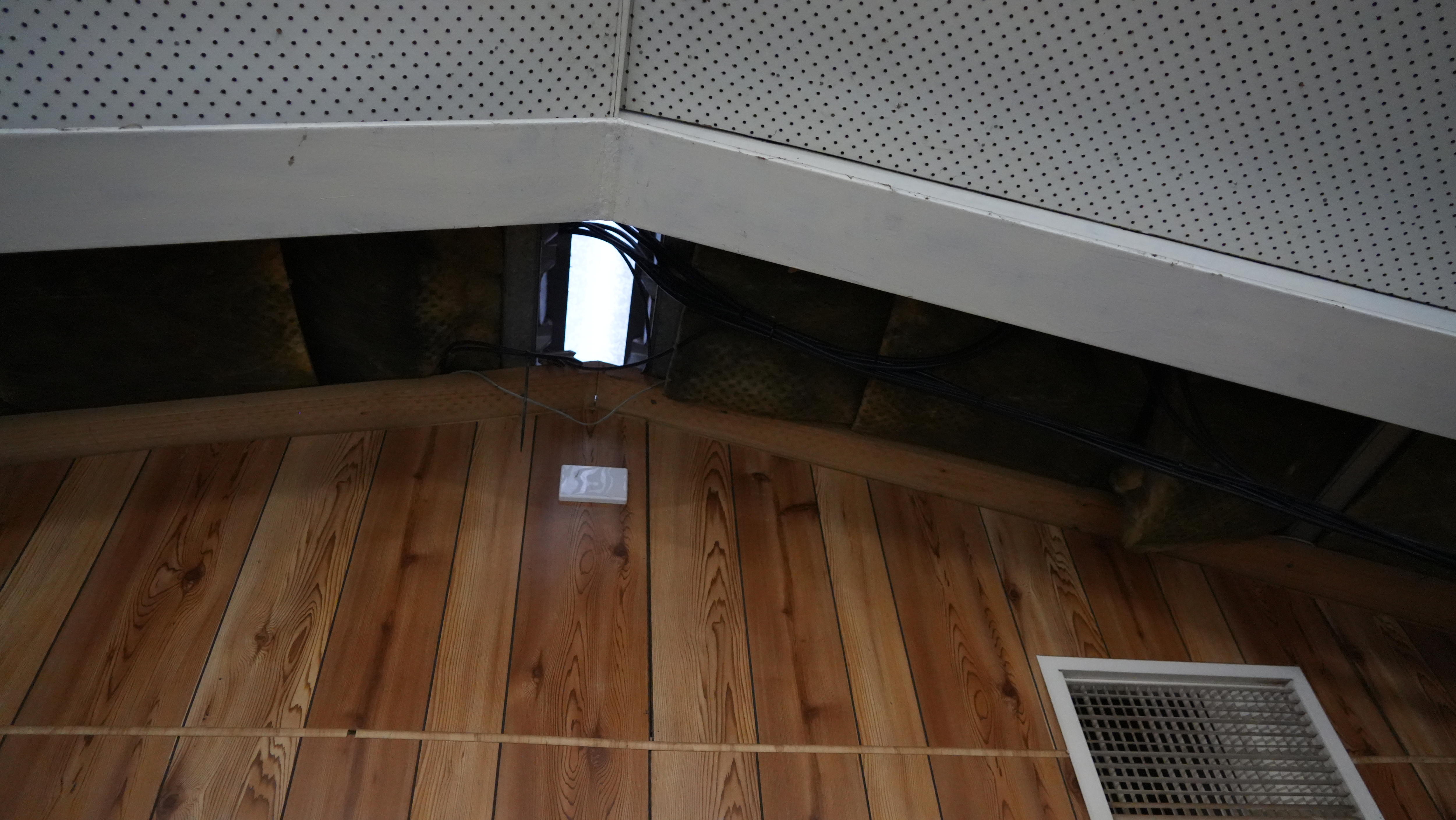 A high ceiling a hole in the roof and wires across it
