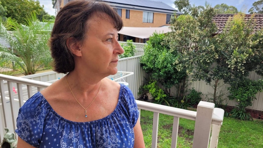 A woman stands on a veranda.