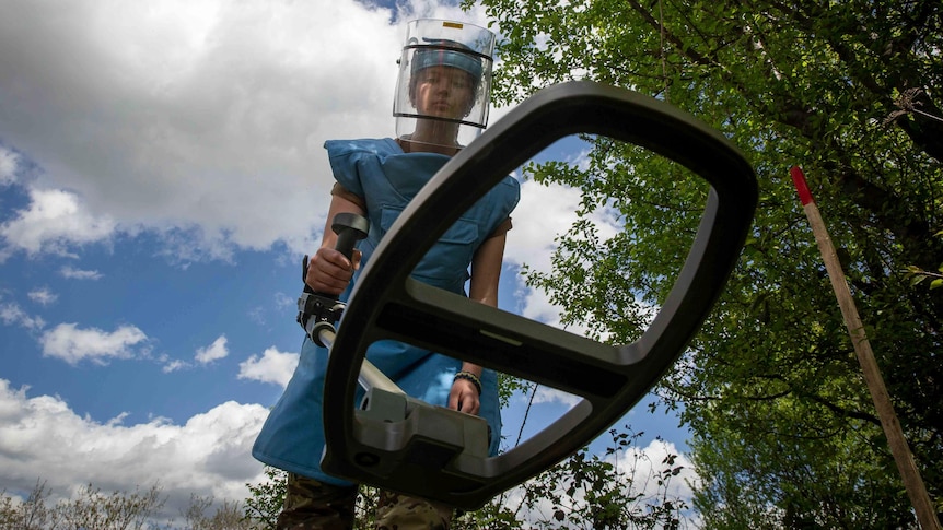 Anastasiia Minchukova sweeps with a mine detector during a training session.