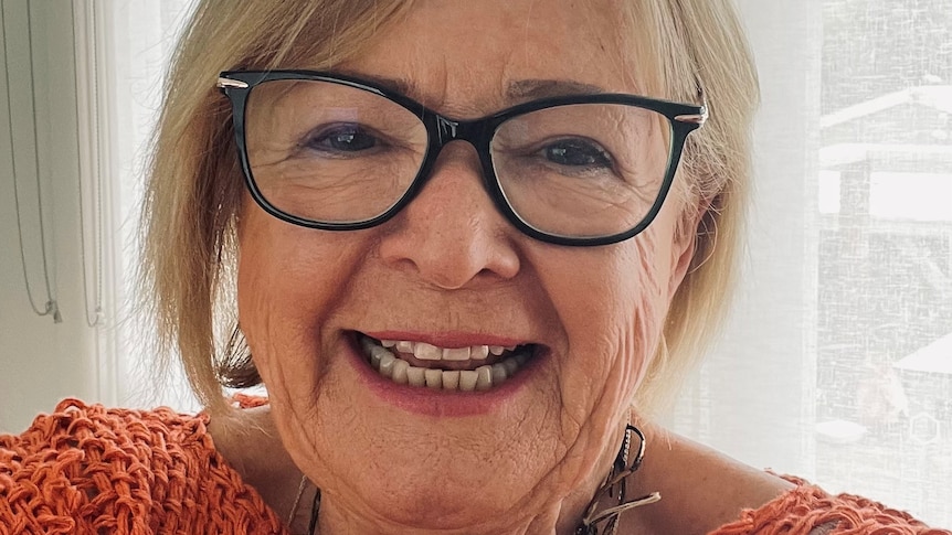 A photo of Marija wearing glasses and an orange knitted jumper smiling