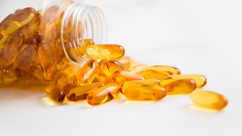 Fish oil capsules spilling from a jar
