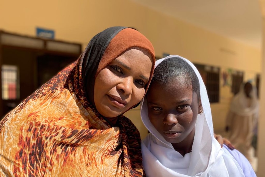 A woman and a girl wearing headscarves smile at the camera after participating in an anti-FGM workshop.