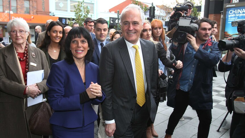 Malcolm Turnbull and Julia Banks walk down the street surrounded by members of the media.