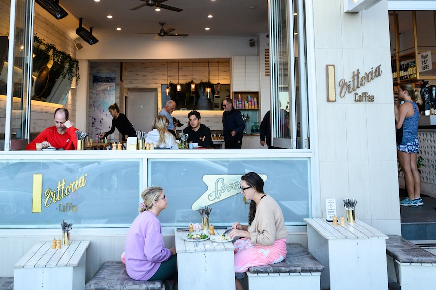 two people sitting at a table outside a cafe