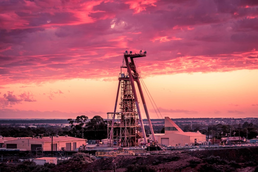 A mine headframe at sunset near an outback town.