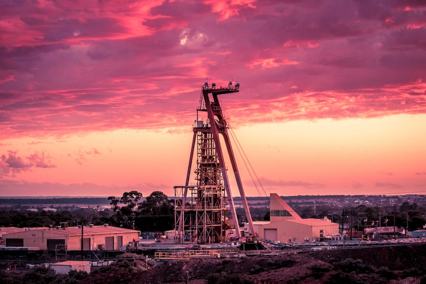 A mining headframe at a gold mine with the sun setting in the background.