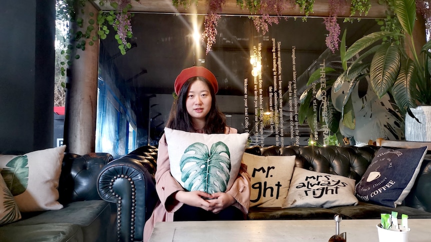 A Chinese girl is sitting in a cafe with colorful decoration.