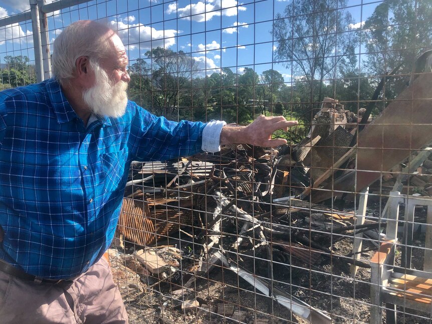 An older man looks at a town that's been ravaged by fire.
