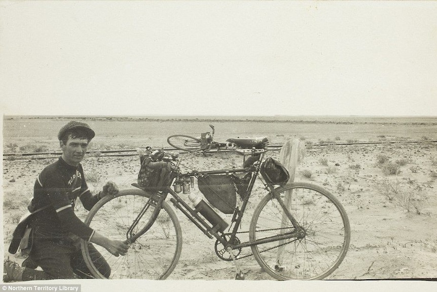 A lone cyclist pictured with his bike in the outback.