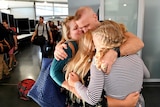 A US Navy commander hugs his two daughters and wife after being on the USS Ronald Reagan for months.