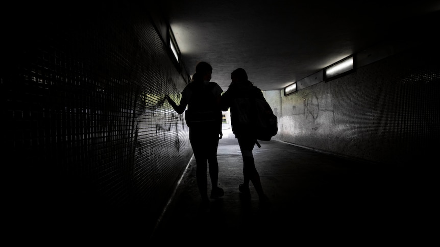 Two young girls walking in a tunnel. 