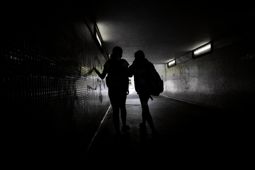 Two young girls walking in a tunnel. 