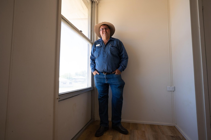 Man in blue shirt standing in room near window