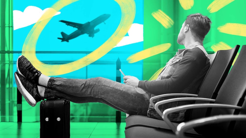 Man at airport lounge with feet up on suitcase, staring out the window at a plane is taking off