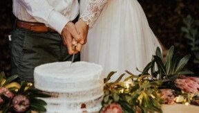 A man and a woman cut a wedding cake.