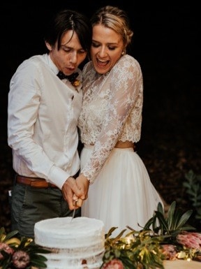 A man and a woman cut a wedding cake.