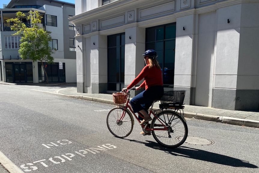 a woman in a red cardigan riding an e-bike on a road 