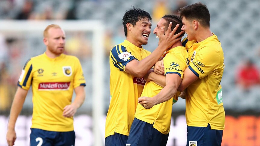 Excited footballers hug a teammate who has just scored a goal in the A-League.