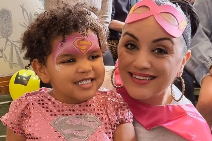 A woman and small girl dressed in pink super hero costumes