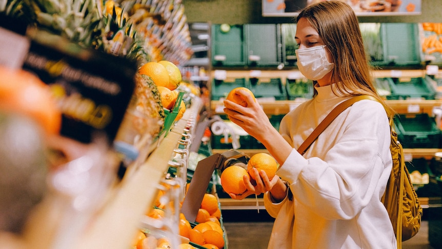 A woman wearing a face mask grocery shops. 