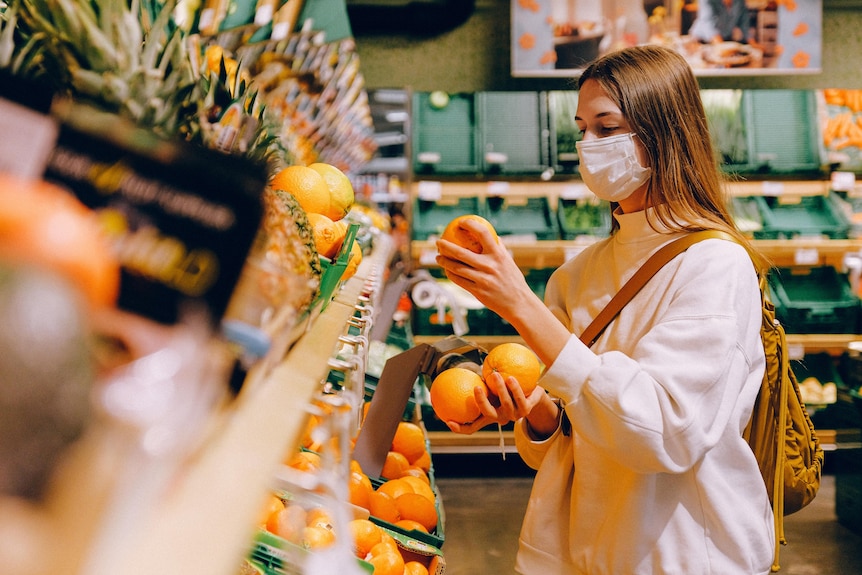 A woman wearing a face mask grocery shops. 