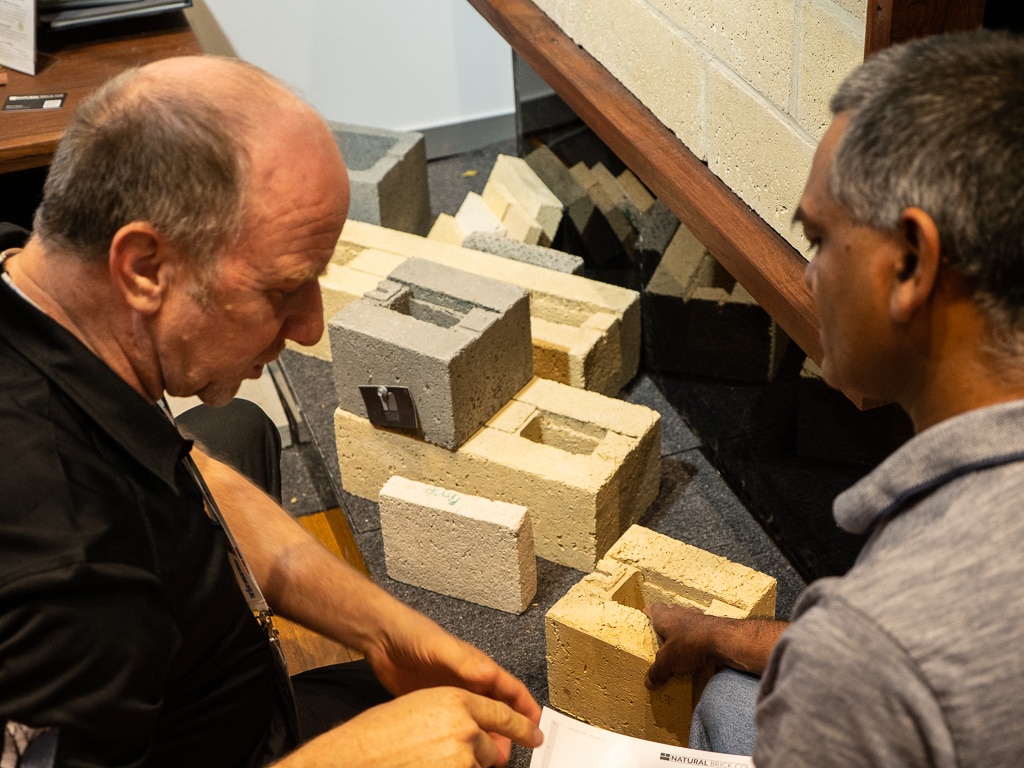 Men discus bricks at the Australian Bushfire Building Conference.
