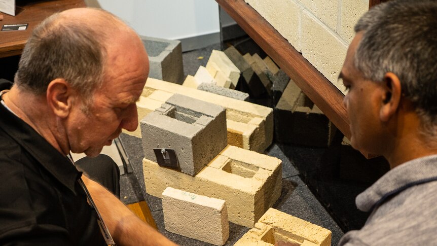 Men discus bricks at the Australian Bushfire Building Conference.