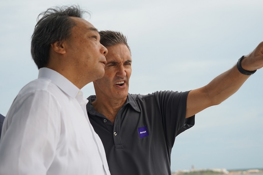 Takayuki Ueda and Inpex site manager stand outside, with the site manager pointing into the distance