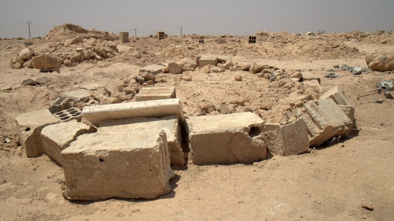 An area of rubble is marked out by a ring of larger stone blocks.
