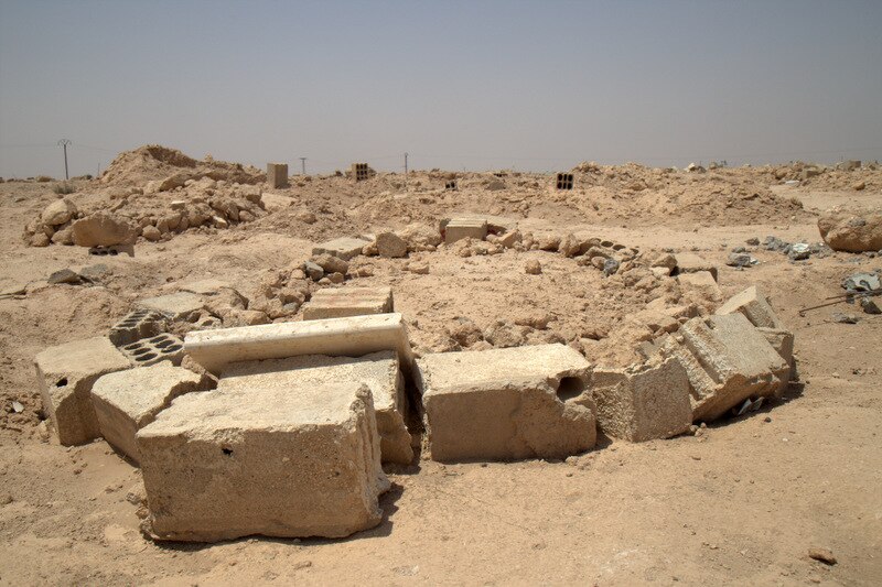 An area of rubble is marked out by a ring of larger stone blocks.