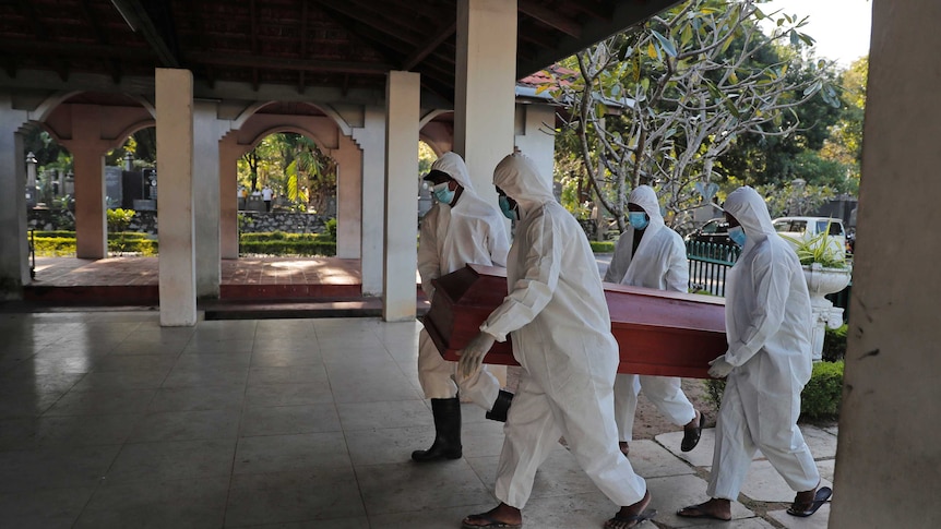 Sri Lankan municipal workers carry the coffin of a COVID-19 victim at a cemetery in Colombo