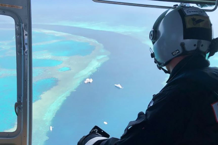 An aerial paramedic looks out of a helicopter at the Barrier Reef below