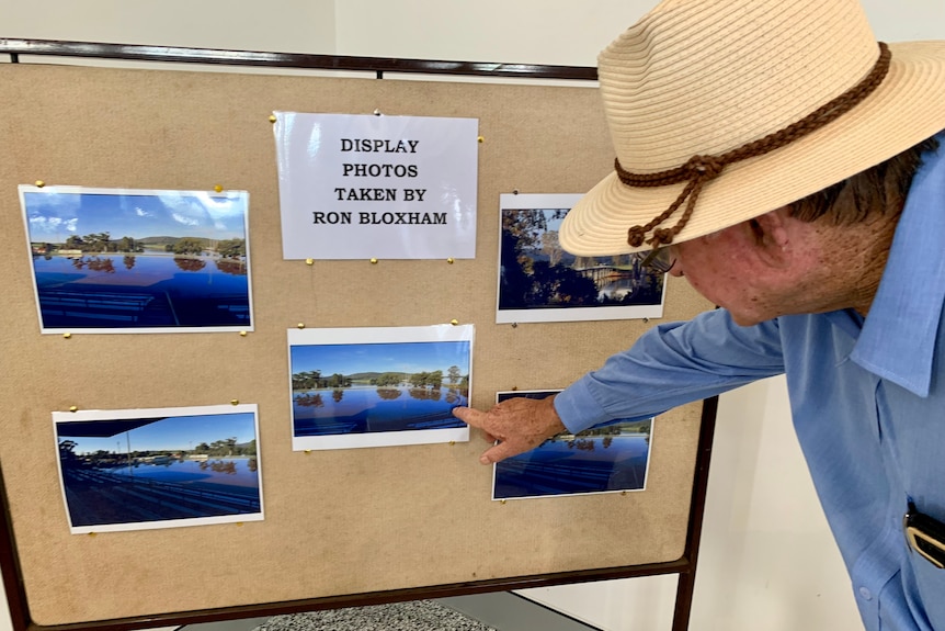 A man points to photos of a flooded showground.