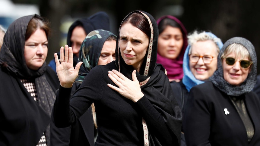 Jacinda Ardern dressed in a head scarf surrounded by Muslim women
